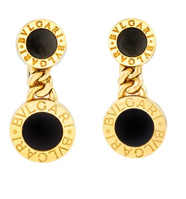 Les boucles d'oreilles dorées et noires sont mises en valeur sur un fond blanc.