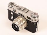 a silver camera sitting on a white surface with a white background
