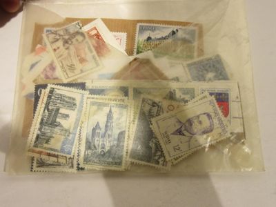 un sachet de timbres posé sur une table, à côté d'une personne tenant une paire de ciseaux