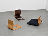 trois chaises et un coussin dans une pièce aux murs blancs