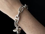 a woman ' s hand holding a chain bracelet