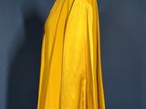 a yellow cape on a mannequin stand against a blue wall