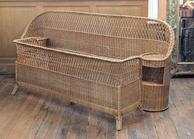 a wicker bench in the middle of a wooden floor