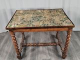 une vieille table en bois avec un plateau à motifs floraux et des pieds tournés