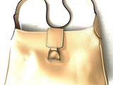 beige leather handbag with a metal buckle on a white background