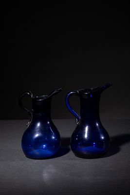 two blue vases sitting on a table in the dark