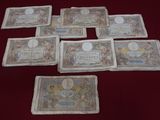 six old french bank notes laid out on a red table