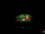 a close up of a green and red fire oplite on a black surface