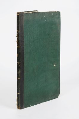 un vieux livre à la couverture verte posé sur une surface blanche