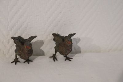 deux petits oiseaux en métal posés sur une surface blanche