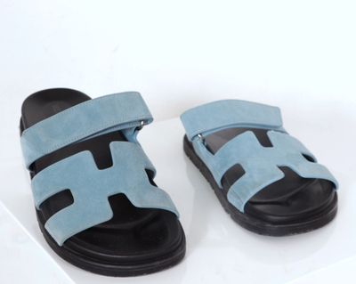 paire de sandales bleu clair avec semelles noires sur une surface blanche