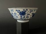 blue and white porcelain bowl on black stand against a gray background