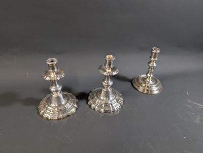 trois bougeoirs en argent posés les uns à côté des autres sur une table