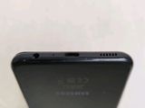 the back of a black cell phone with a small hole in the middle