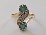 gros plan d'une bague en or avec une pierre verte