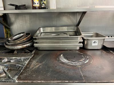 Plusieurs casseroles et poêles sont posées sur une cuisinière dans une cuisine.