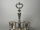 an antique silver plated tea set with four cups on a stand