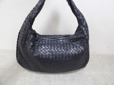 the black leather bag is sitting on a table with a white background