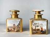 pair of antique oil bottles with a painting of a man and a woman in a landscape