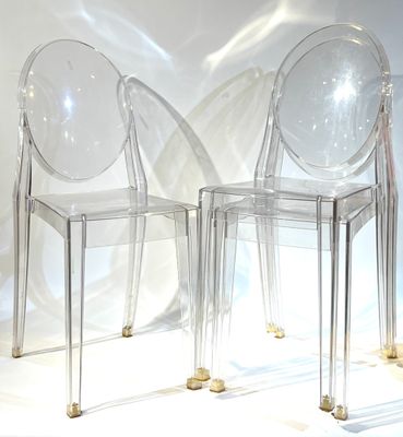 deux chaises transparentes placées l'une à côté de l'autre sur une surface blanche