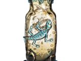 a glass vase with a lizard on it on a white surface