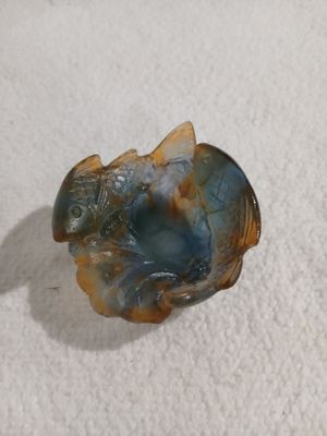 a small glass fish sitting on a white surface