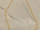 a close up of a pearl necklace on a white cloth