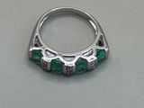 an image of a silver ring with green stones