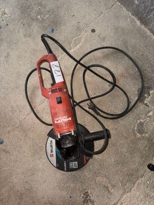 une petite perceuse électrique posée par terre à côté d'un tuyau d'arrosage