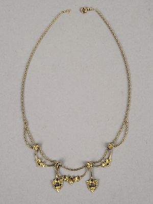 a gold plated necklace with flowers and leaves on a chain