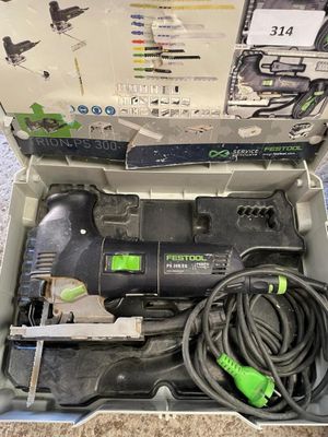 une boîte contenant une perceuse filaire, posée par terre