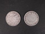 two silver coins on a black surface