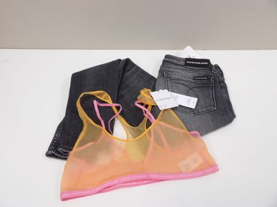 deux paires de jeans et un haut de soutien-gorge posés sur une table blanche