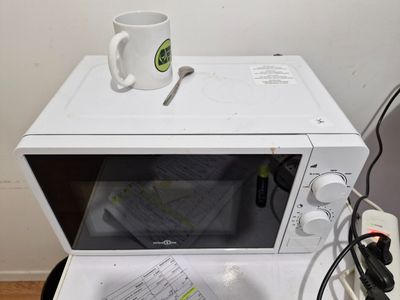 un micro-ondes blanc sur lequel est posée une tasse
