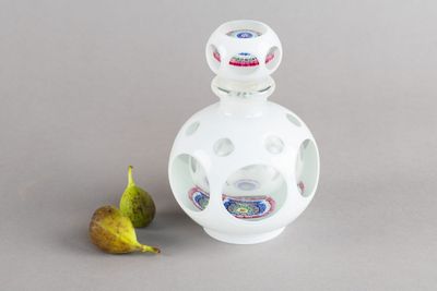 une bouteille en verre décorée, à côté d'une figurine