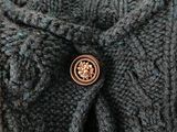 a close up of a knitted sweater with a button on it