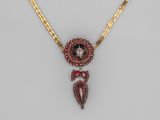 un collier en or et grenat avec un pendentif en pierre rouge
