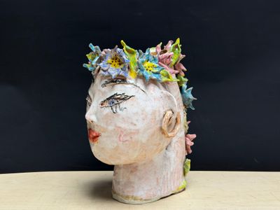 une tête en céramique ornée de fleurs, posée sur une table