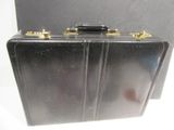a black suitcase with gold handles on a white surface