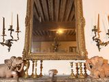 une cheminée sur laquelle sont posés un miroir, des bougies et des statues