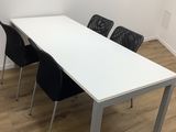 two black chairs sit at a white table in an empty room