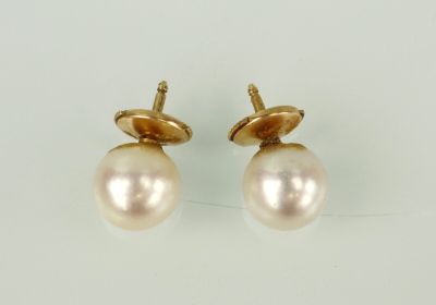 une paire de boucles d'oreilles en perles et en or posées sur un fond blanc