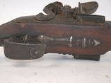 a wooden toy gun with a metal handle on a white surface