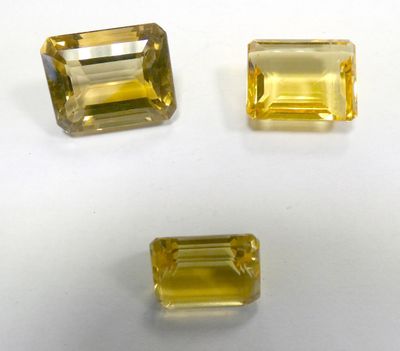 three yellow sapphires on a white surface