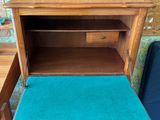 an old wooden desk with a blue cushion on top of it