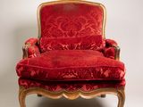 une image représentant une chaise rouge avec un cadre doré et un revêtement rouge