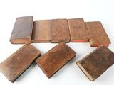 several old books are lined up on a white surface