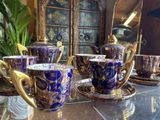 several cups and saucers are sitting on a table in front of a cabinet