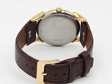a close up of a watch on a white surface with a brown strap