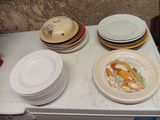many plates and bowls on the counter top of the refrigerator